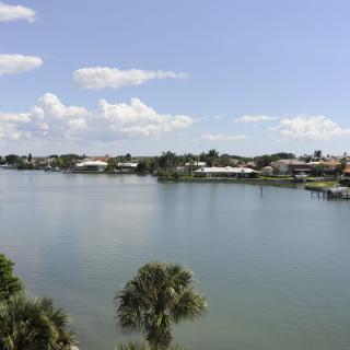 A scenic view of a calm lake surrounded by residential homes under a clear blue sky.