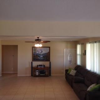 A spacious living room featuring a comfortable sofa, ceiling fan, and ample natural light.