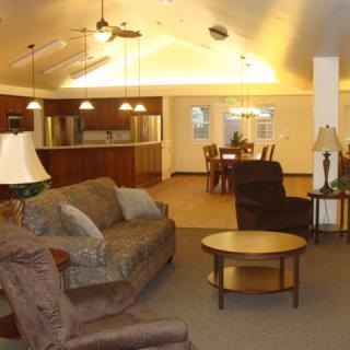 A cozy living room with sofas, chairs, and a central table under warm lighting.