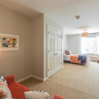 A cozy bedroom with a bed, closet, and natural light from a large window.