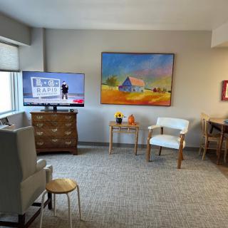 A cozy living room with a television, artwork, and comfortable seating.