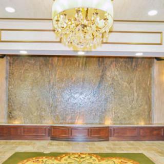 A luxurious lobby with a large chandelier and an elegant water feature against a marble wall.