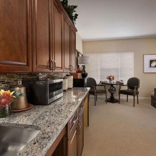 A modern kitchen with wood cabinets and granite countertops, leading to a cozy dining area.