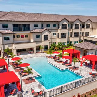 Luxury apartment complex with a swimming pool and red cabanas.