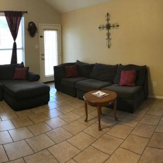 A cozy living room with a sectional sofa and a small wooden coffee table on tiled flooring.