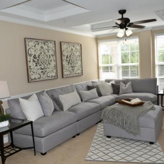 A modern living room featuring a large gray sectional sofa, artistic wall decor, and a cozy rug.