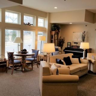 A cozy living room with a seating area, piano, and large windows.