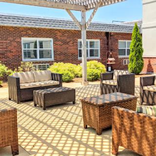 A cozy outdoor seating area featuring modern wicker furniture under a sunshade.