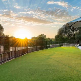 A serene sunset view over a grassy outdoor area with a fence lining the scene.