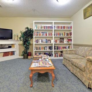 A cozy living room with a sofa, coffee table, TV, and a well-stocked bookshelf.