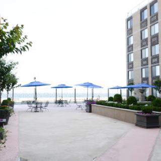 A serene outdoor patio area of a hotel, featuring blue umbrellas and a scenic view of the water.