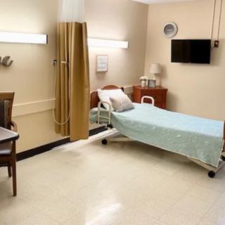 A clean and well-organized hospital room with a single bed and furniture.