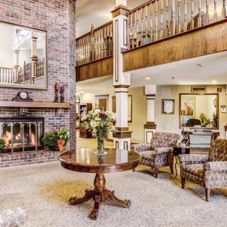 A spacious living room featuring a brick fireplace, elegant furniture, and a decorative table with flowers.