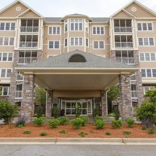 A front view of a multi-story residential building with a covered entrance and landscaped surroundings.