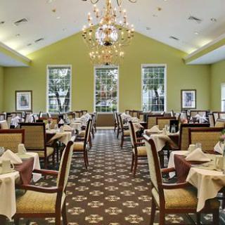 Elegant dining room interior with neatly arranged tables and chairs under a chandelier.