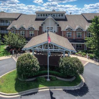 Front view of a large building with an entrance driveway and landscaped greenery.