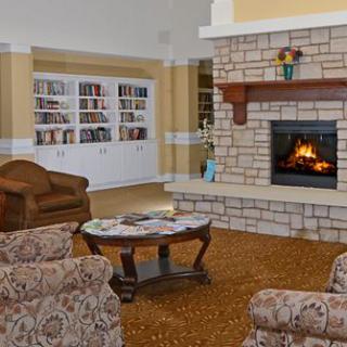 A cozy living room featuring a stone fireplace, armchairs, and bookshelves.