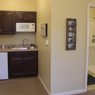 A small kitchen area featuring dark cabinets, a white microwave, and a sink.