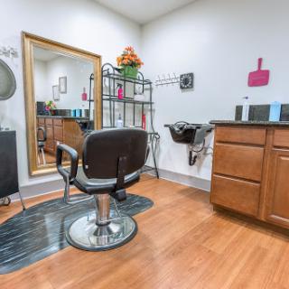 A cozy and well-organized hair salon interior with a barber chair, mirror, and various styling products.