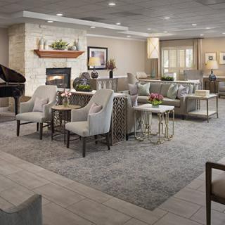 A cozy lounge area featuring elegant furniture, a fireplace, and a grand piano.