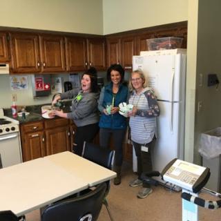 A group of three friends enjoying a cooking session in a cozy kitchen.