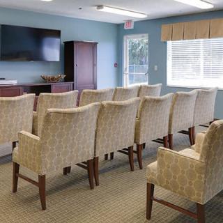 A small conference room with rows of chairs facing a TV.
