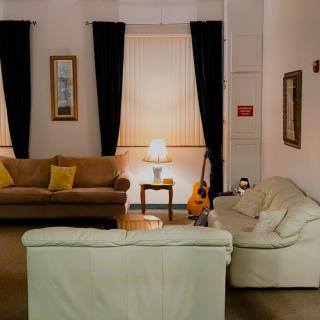 A cozy living room with two sofas, a guitar, and a lamp softly illuminating the space.