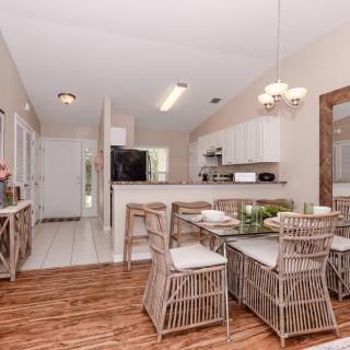 A modern kitchen and dining area with wooden floors and wicker furniture.