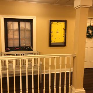 A hallway with a railing, featuring framed artwork and decor.