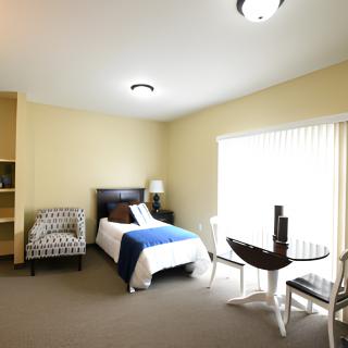 A cozy bedroom with a single bed, an armchair, and a small table by the window.