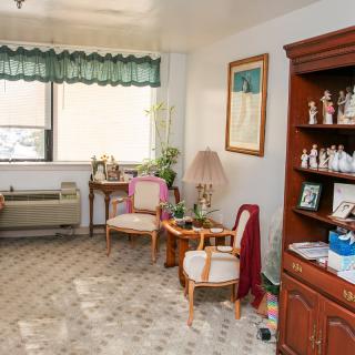 A cozy living room with chairs, a lamp, and decorative shelves.