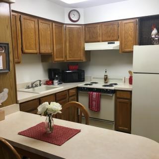 A cozy kitchen with wooden cabinets, appliances, and a countertop adorned with flowers.