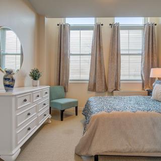 A cozy bedroom with a stylish dresser and large windows.
