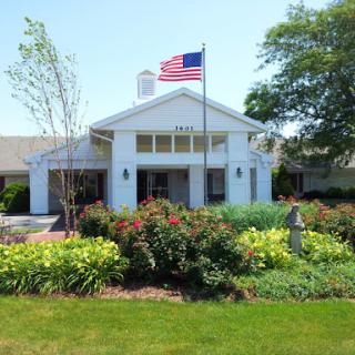 A welcoming entrance featuring an American flag and beautifully landscaped gardens.
