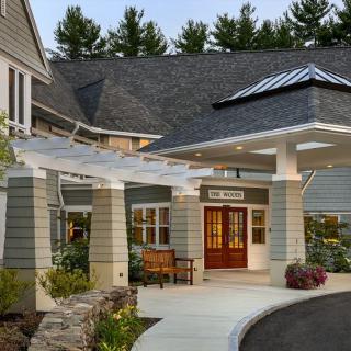 A welcoming entrance to a modern building, featuring a covered porch and landscaped pathway.