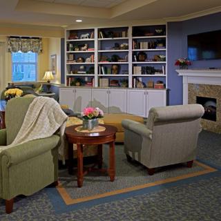 A cozy living room with armchairs, a fireplace, and a large bookshelf.