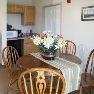 A cozy dining area with a wooden table, surrounded by chairs and adorned with a floral centerpiece.