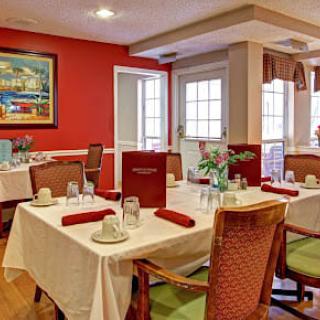 A cozy dining room with elegantly set tables and comfortable chairs.