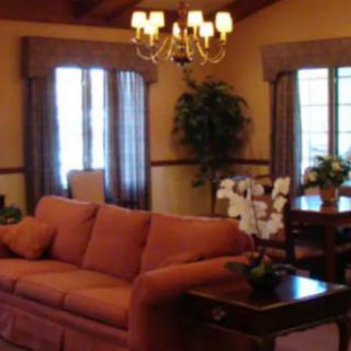 A cozy living room with a sofa, chandelier, and dining area.