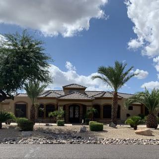 A beautiful house surrounded by palm trees under a partly cloudy sky.