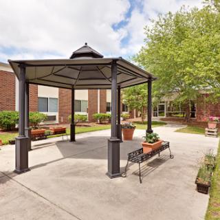 A serene outdoor gazebo surrounded by greenery in a courtyard setting.