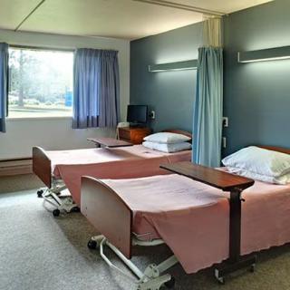 A hospital room with two patient beds and a window providing natural light.