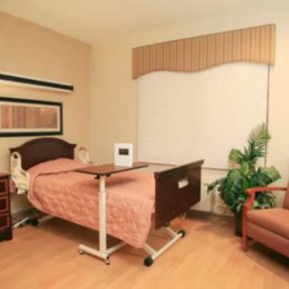 A hospital room with a bed, a side table, and seating area.