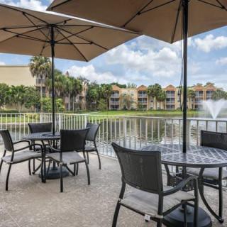 A scenic outdoor patio area with tables and umbrellas overlooking a lake with a fountain.