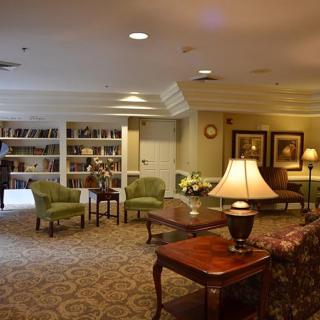 A cozy living room with a library section, featuring comfortable seating and warm lighting.