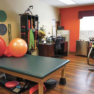 A well-equipped physical therapy room with exercise balls and various rehabilitation tools.