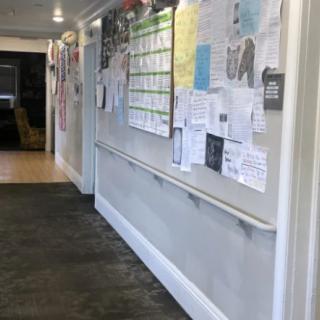 A hallway with a bulletin board displaying various notices and information.