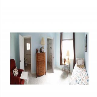 A cozy bedroom with a dresser, window, and comfortable chair.