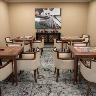 A neat and organized room with elegant tables and chairs, adorned with artwork on the walls.