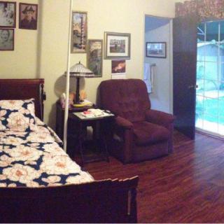 A cozy bedroom with a bed, recliner, and various wall decorations.